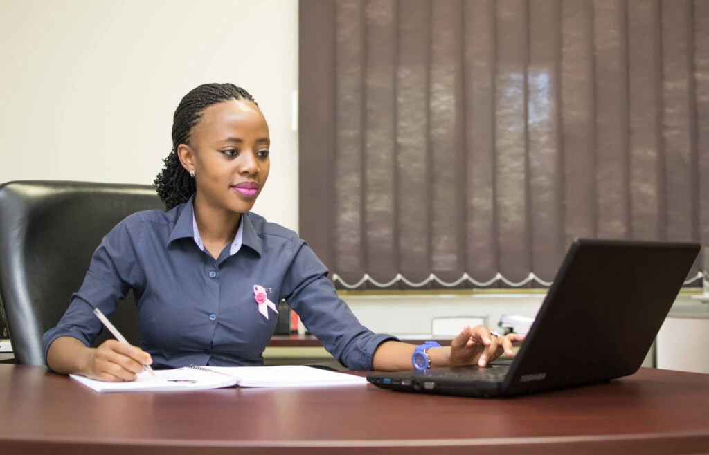 Accountant Sitting on A computer writing in her notebook
